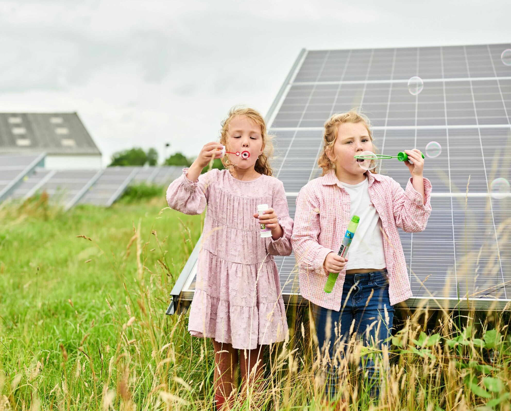 Twee kinderen staan op een zonnepark en blazen bellen